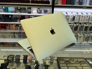 Apple laptop on display in a store with shelves in the background.