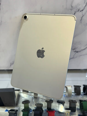 A silver Apple iPad Pro shown from the back, resting on a clear display stand in front of a white marble-patterned background.