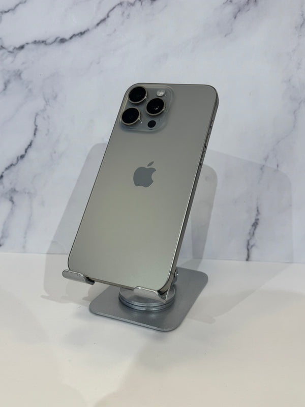 A silver Apple iPhone 12 Pro shown from the back, resting on a small metallic stand against a white marble-patterned background.