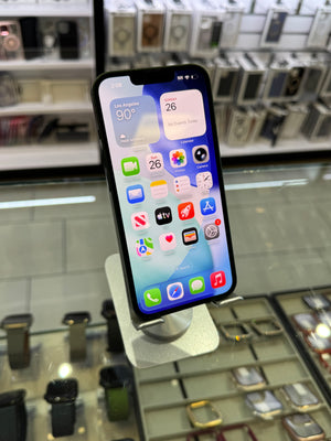 A black iPhone with its home screen visible, mounted on a white display stand inside a retail store.
