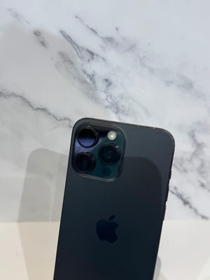 A dark gray Apple iPhone showing the back camera module and logo, resting on a white surface against a white marble-patterned background.
