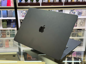 Black laptop with Apple logo on a glass surface in a store setting