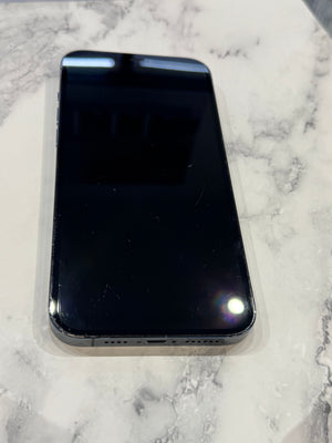 A black smartphone with a glossy screen, shown from the back, resting on a white and gray marble-patterned surface.