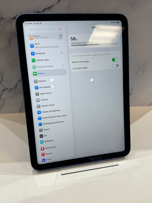 A black iPad with rounded corners displaying the Settings app on a white surface, with a marble-patterned background.