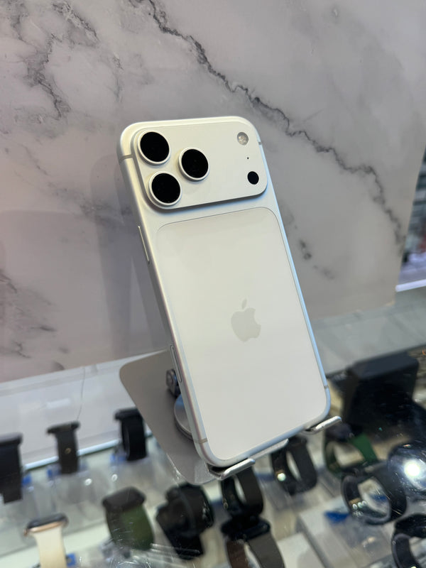 A white Apple iPhone with a large camera module, shown from the back on a display stand in front of a marble-patterned background.