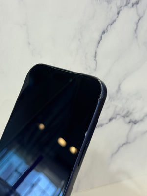 Close-up of a black smartphone corner resting on a white marble-patterned surface.