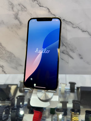 A black smartphone with a lit blue and pink 'hello' home screen, displayed on a silver stand in front of a white marble-patterned background.