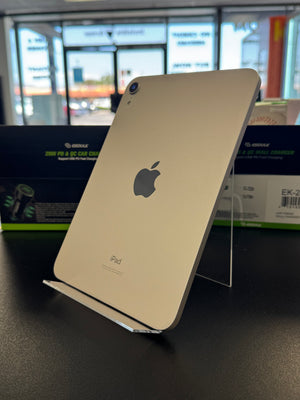 A silver Apple iPad shown from the back resting on a clear display stand on a dark table.