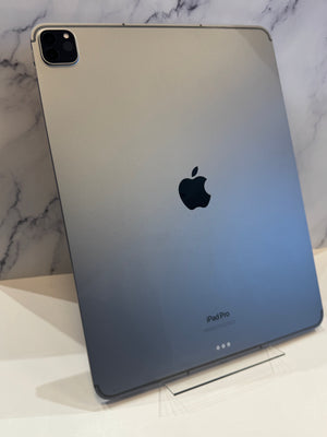 A silver Apple iPad Pro resting on a clear acrylic stand against a white marble background.