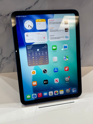 A black Apple iPad Pro standing upright on a white display stand against a light gray marble-patterned background.