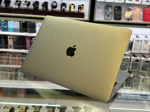 Gold laptop with Apple logo on a reflective surface in a store setting
