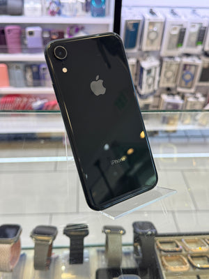 Black smartphone with Apple logo on a reflective surface, with a store interior in the background