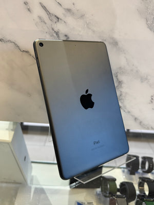 An Apple iPad shown from the back, standing on a clear display stand against a white marble-patterned wall.