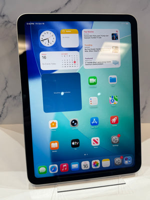 An Apple iPad tablet with a black bezel, standing upright on a clear display stand against a light marble-patterned background.