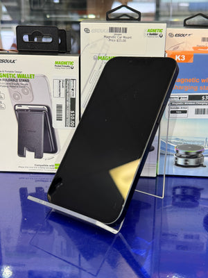 Black phone case on a display stand with product packaging in the background