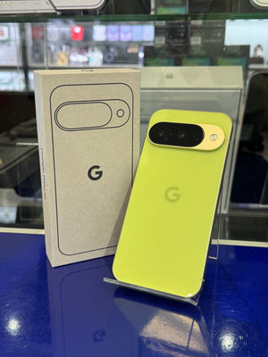 Yellow smartphone with gold accent on a clear stand next to its packaging