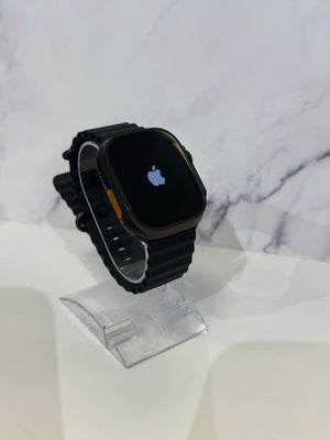 A black Apple Watch with a black band displayed on a clear stand against a white marble-patterned background.