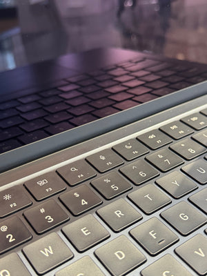 Close-up of a laptop keyboard with it reflecting on the laptop black screen.