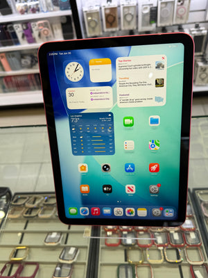 A tablet with a black bezel and a red outer frame, displaying a colorful home screen, photographed in a retail store setting with shelves of accessories in the background.