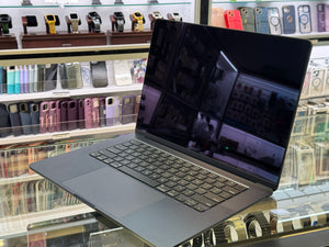 Laptop on a glass surface with a store shelf of phone cases in the background