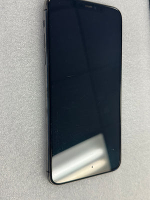 A black smartphone with a large black screen, shown from the front on a light gray textured surface.