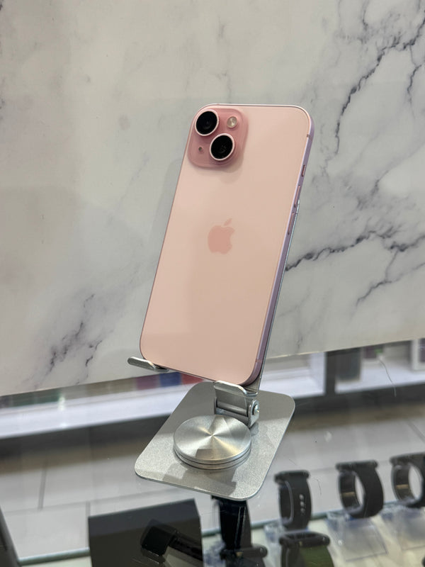 A rose gold Apple iPhone 12 Pro displayed on a silver metal stand, showing its back panel and dual camera system against a marble-patterned background.