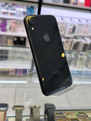 Black smartphone with Apple logo on a transparent stand against a blurred store background