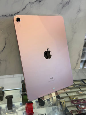 A gold Apple iPad shown from the back, leaning against a marble-patterned wall in a retail display.