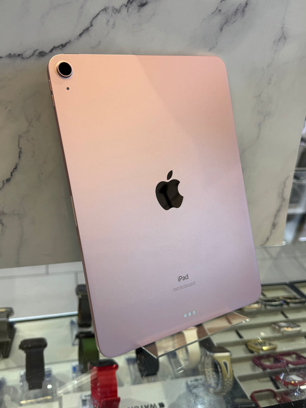 A gold Apple iPad shown from the back, leaning against a marble-patterned wall in a retail display.