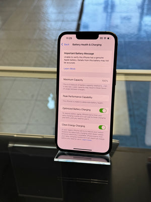 iPhone displaying battery health on a stand on a reflective background