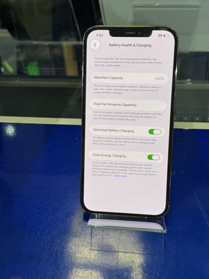 Smartphone displaying battery health and charging information on a reflective surface.