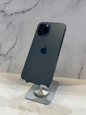 A dark blue-gray Apple iPhone with a triple-camera system, displayed on a silver stand against a white marble-patterned background.