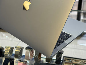 Close-up of a laptop with an Apple logo on a reflective surface