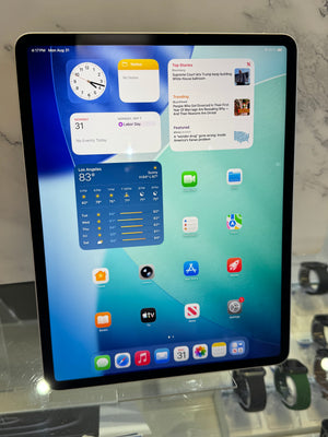 A tablet device with a black bezel and a colorful home screen, displayed upright on a stand in a retail or showroom setting.