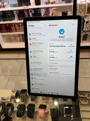 Tablet displaying device care settings on a store shelf with watches below