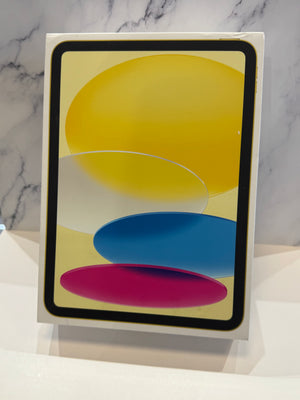 An Apple iPad in its original white retail box, standing upright against a white surface with a gray marble-patterned background.