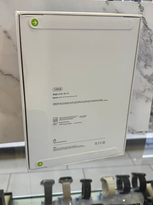 The back of an Apple iPad Air (M2) box, showing product specifications and regulatory text, displayed on a store counter.