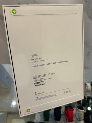 The back of a white Apple iPad 128GB Wi-Fi retail box, showing product specifications and barcodes, photographed in a store setting.