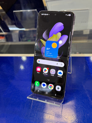 Samsung Galaxy Z Flip phone displayed on a stand with a blue background