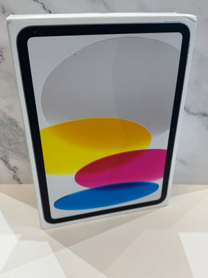 A white Apple iPad in its original retail box, standing upright against a light marble-patterned background.