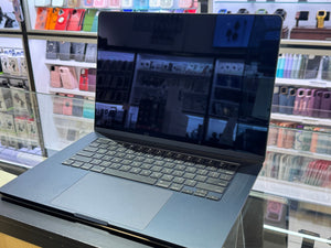 Laptop on a table with shelves displaying colorful items in the background
