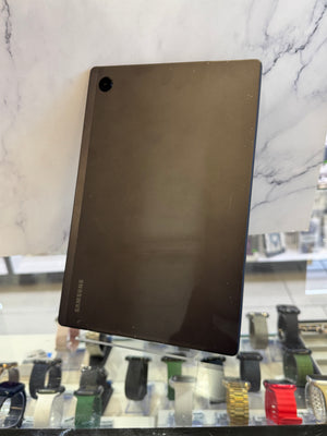 A dark brown rectangular tablet or electronic device with a small circular cutout in the top-left corner, displayed on a stand in front of a marble-patterned background.