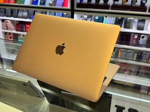 Gold laptop with Apple logo on a display stand in a store