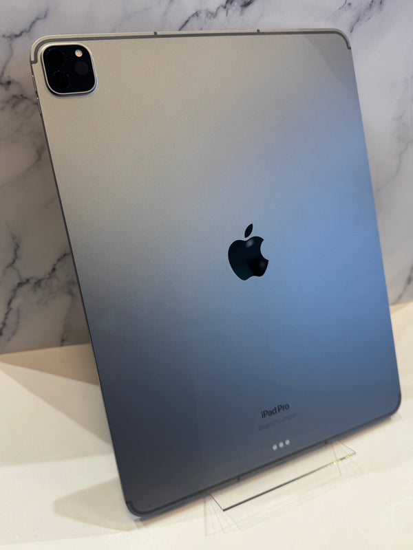 A silver Apple iPad Pro standing upright on an acrylic stand against a white marble background. 
