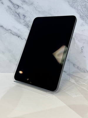 A black tablet with rounded corners displayed upright on a clear acrylic stand against a white marble-patterned background.