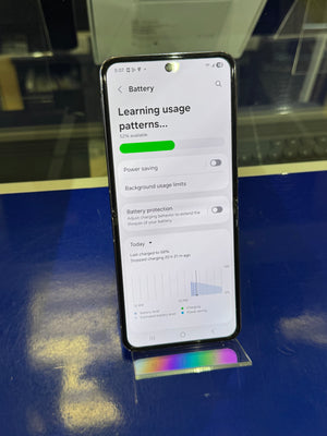 Smartphone displaying battery usage settings on a reflective surface