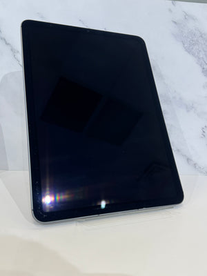 A black tablet with a glossy screen, standing upright on a clear acrylic stand against a white marble-patterned background.