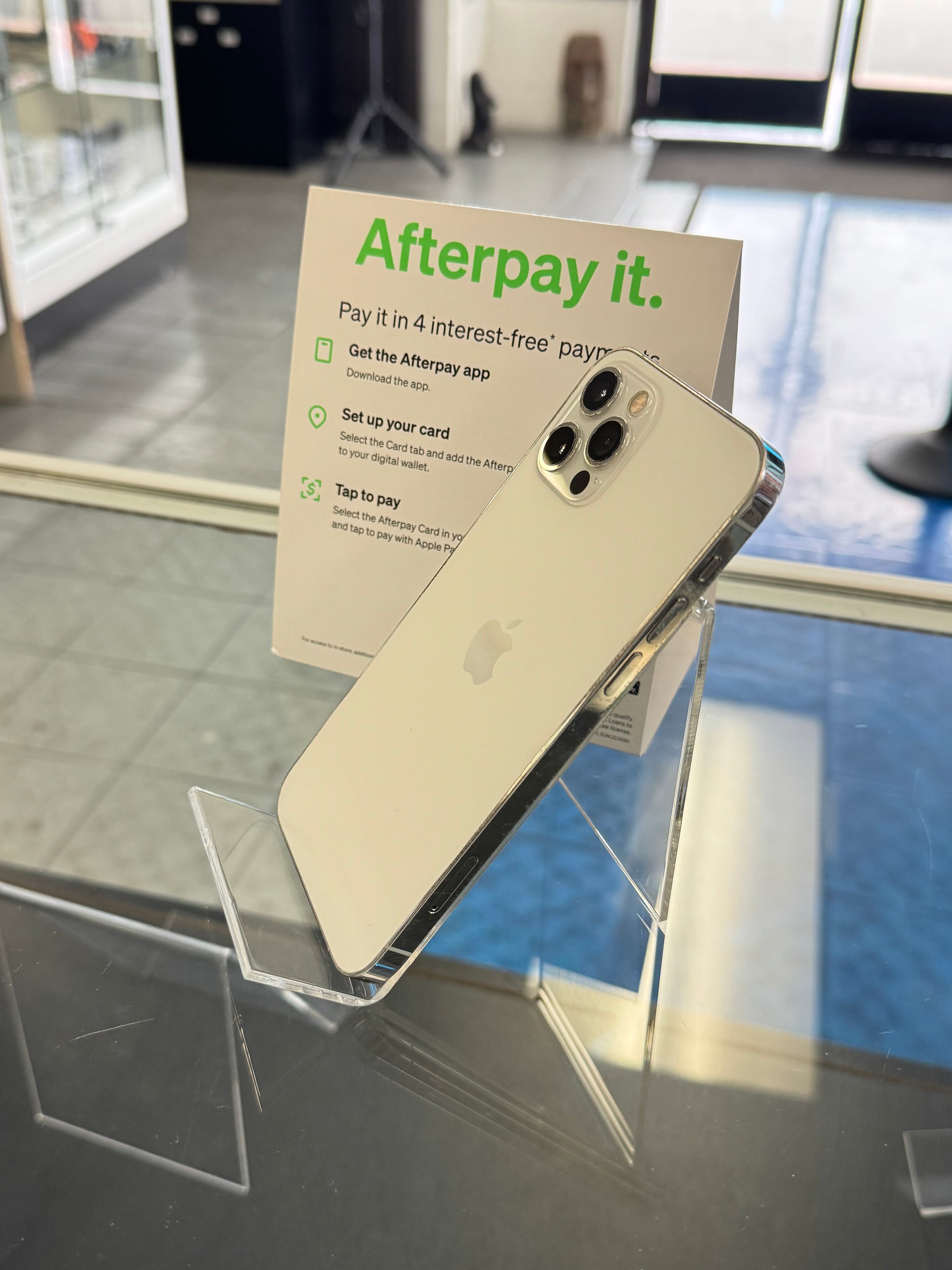 Gold smartphone on a stand with 'Afterpay it.' sign in the background