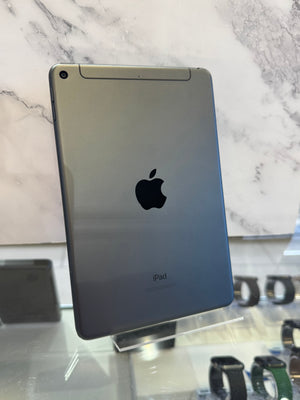An Apple iPad shown from the back, standing on a clear display stand in a retail setting with a marble-patterned wall behind it.