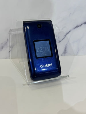 A glossy blue Alcatel flip phone in a closed position resting on a clear acrylic stand against a white background. 